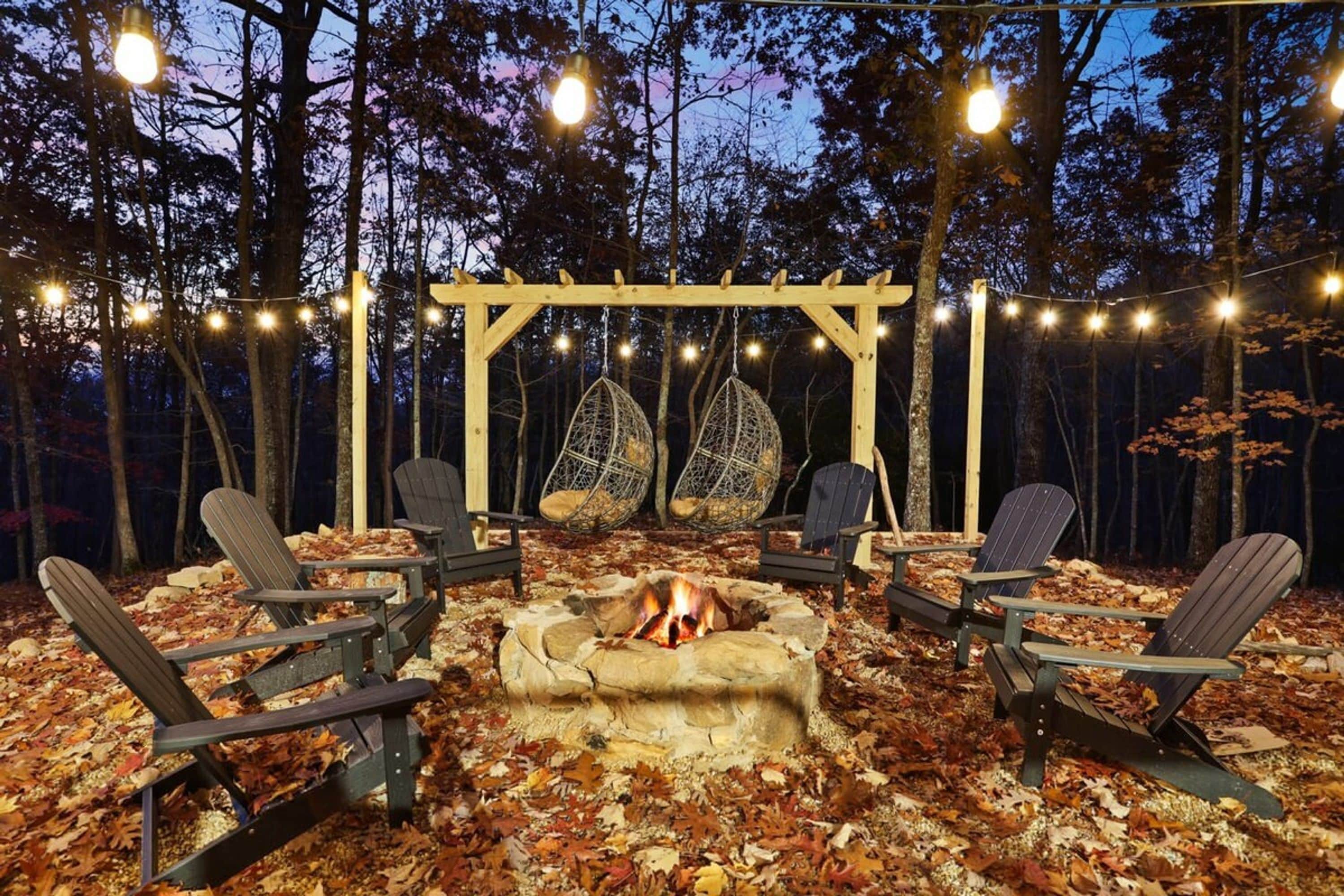 Een terras met Adirondack-stoelen, een vuurkorf en lichtslingers.