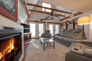 Una sala de estar con chimenea, ventilador de techo, sofá y mesa de centro.