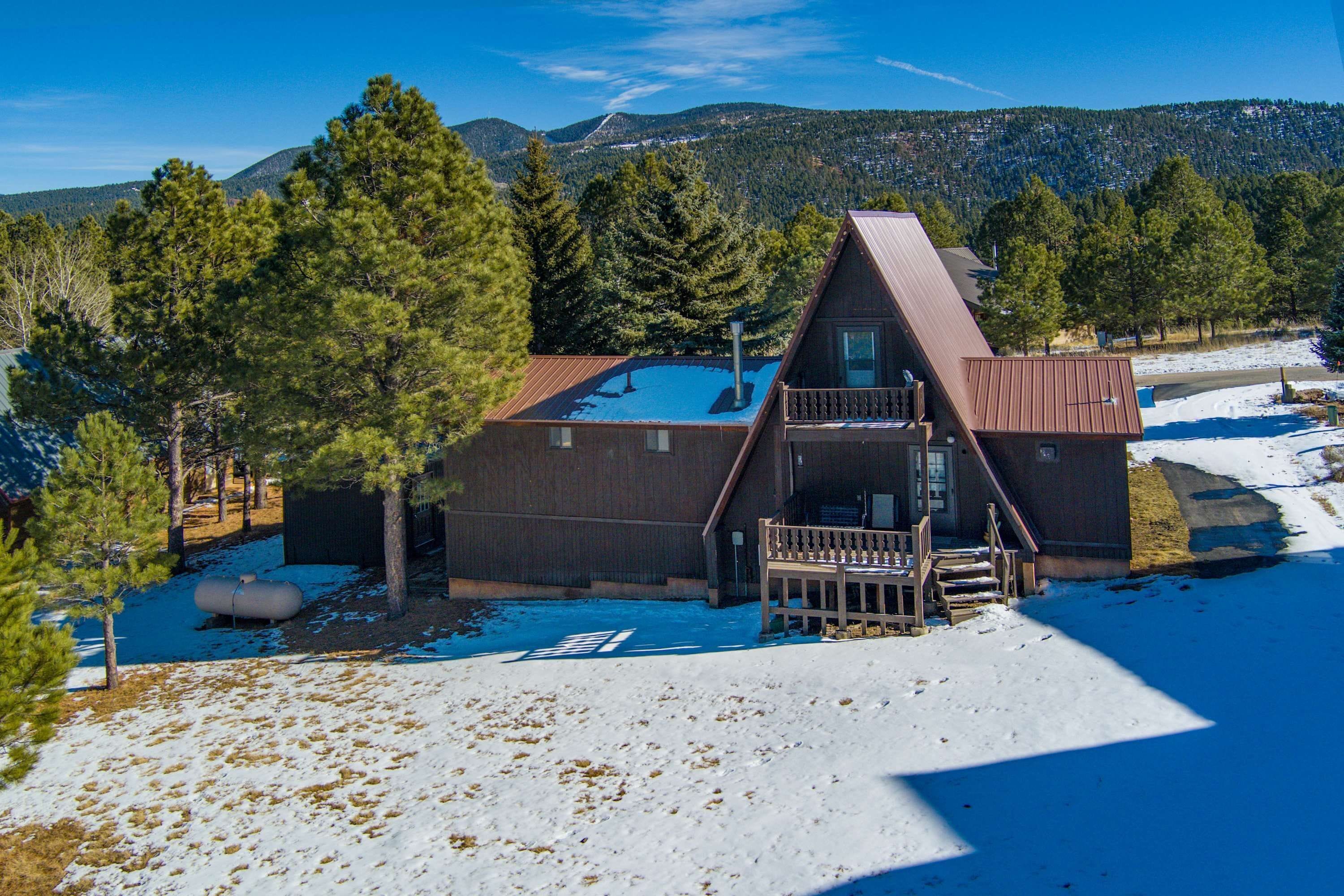 A cabin with a sloped roof, a balcony, and a snow-covered ground.
