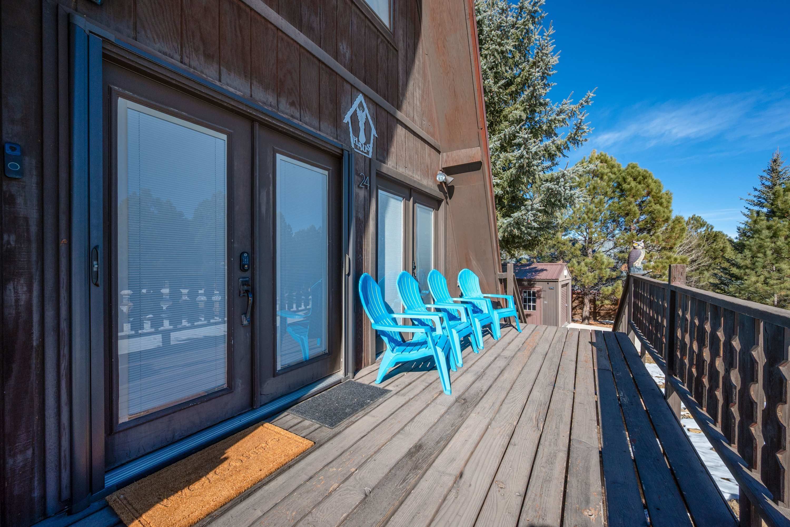 A wooden deck with blue chairs and a small building with a sign.