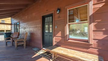A wooden cabin with a porch, a door, and a window with blinds.