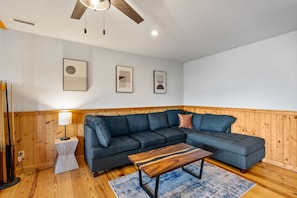 A modern living room with a sectional sofa, a wooden coffee table, and a lamp. - 7 min to Hatley Pointe Views Hot Tub 2 Decks (Mars Hill)