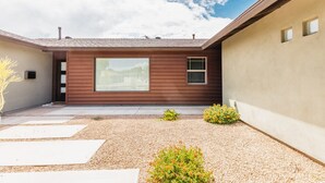 A modern house with a large window, a gravel driveway, and a small garden with plants. - Right Near Old Town 4BR With Heated Pool (Scottsdale)