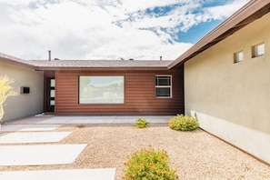 A modern house with a large window, a gravel driveway, and a small garden with plants. - Right Near Old Town 4BR With Heated Pool (Scottsdale)