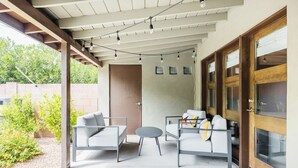 An outdoor patio with two sofas, a small round table, and string lights. - Right Near Old Town 4BR With Heated Pool (Scottsdale)