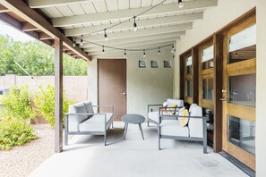 An outdoor patio with two sofas, a small round table, and string lights. - Right Near Old Town 4BR With Heated Pool (Scottsdale)