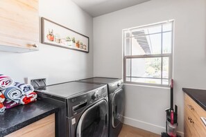 A laundry room with a washing machine, dryer, and a window with a view of a staircase. - Right Near Old Town 4BR With Heated Pool (Scottsdale)