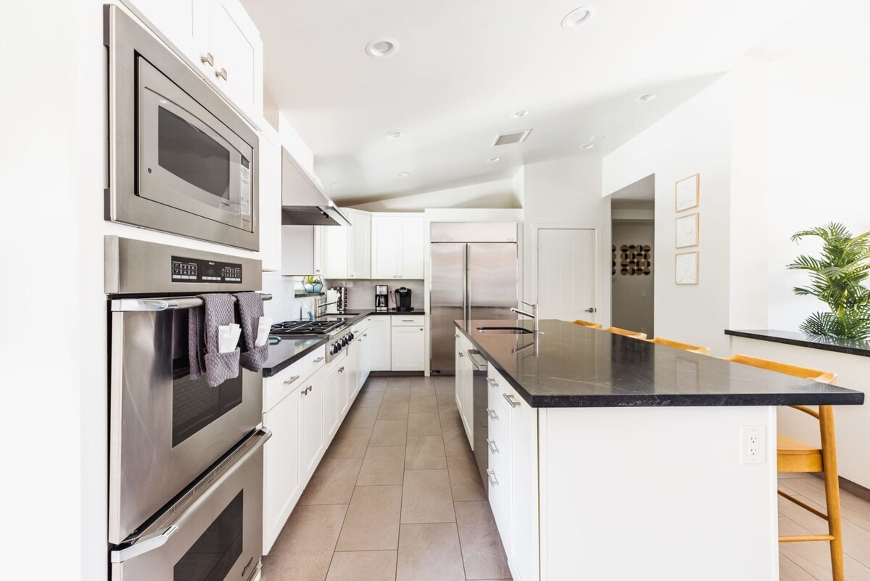 A modern kitchen with stainless steel appliances, white cabinetry, and a black countertop.