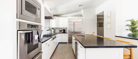 A modern kitchen with stainless steel appliances, white cabinetry, and a black countertop.