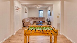 A room with a foosball table, a sectional sofa, and a basketball hoop. - Valley Retreat Sleeps 10 Hot Tub Fire Pit (Blue Ridge)