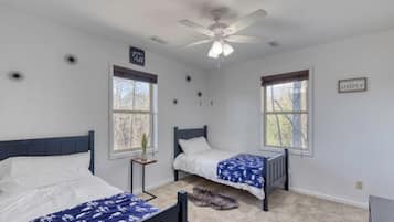 A bedroom with two beds, a ceiling fan, and two windows.