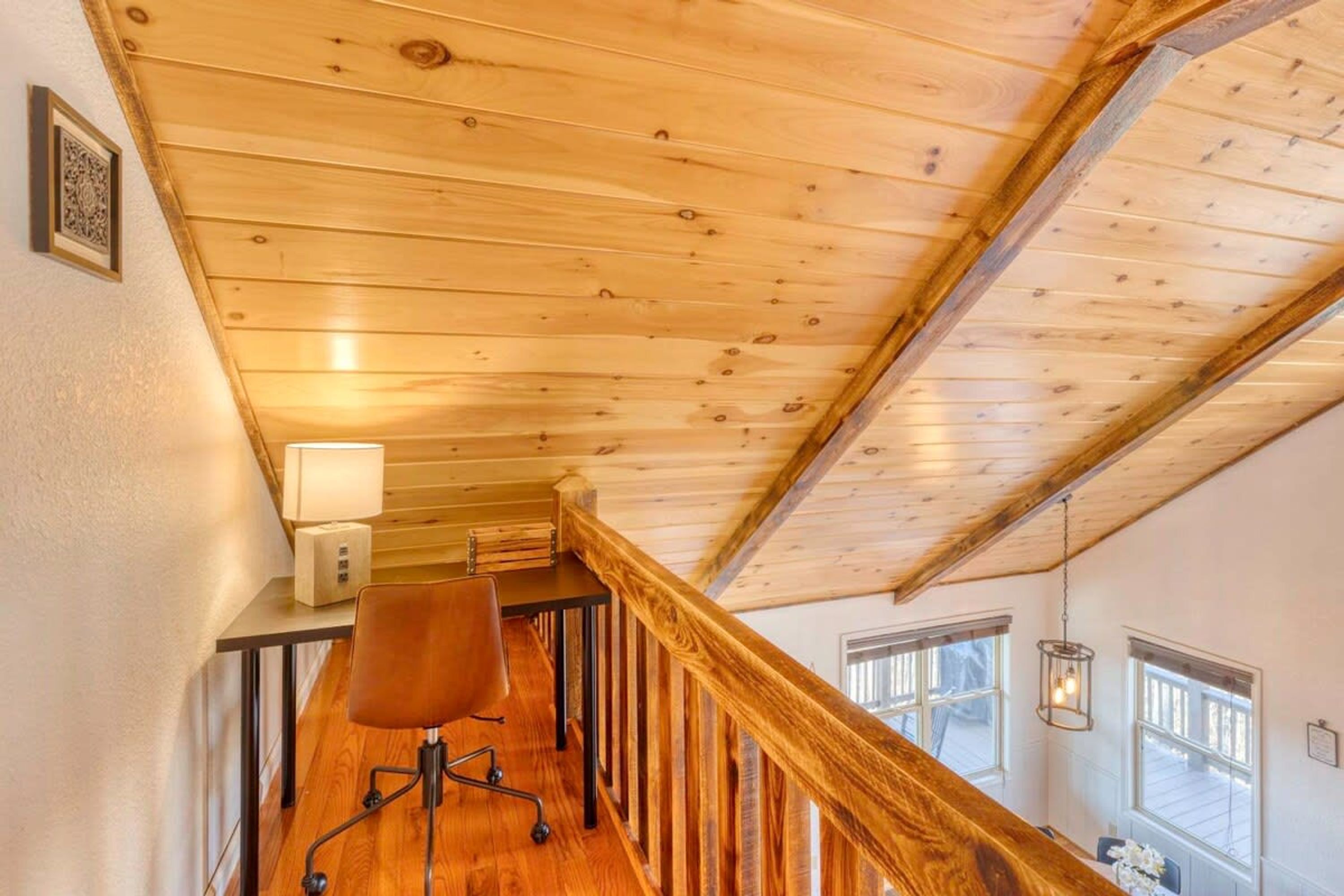 A wooden staircase with a desk and chair, a lamp, and a window with a view.