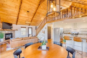 A spacious living area with a wooden ceiling, a fireplace, a dining table with chairs, and a kitchen area. - Valley Retreat Sleeps 10 Hot Tub Fire Pit (Blue Ridge)