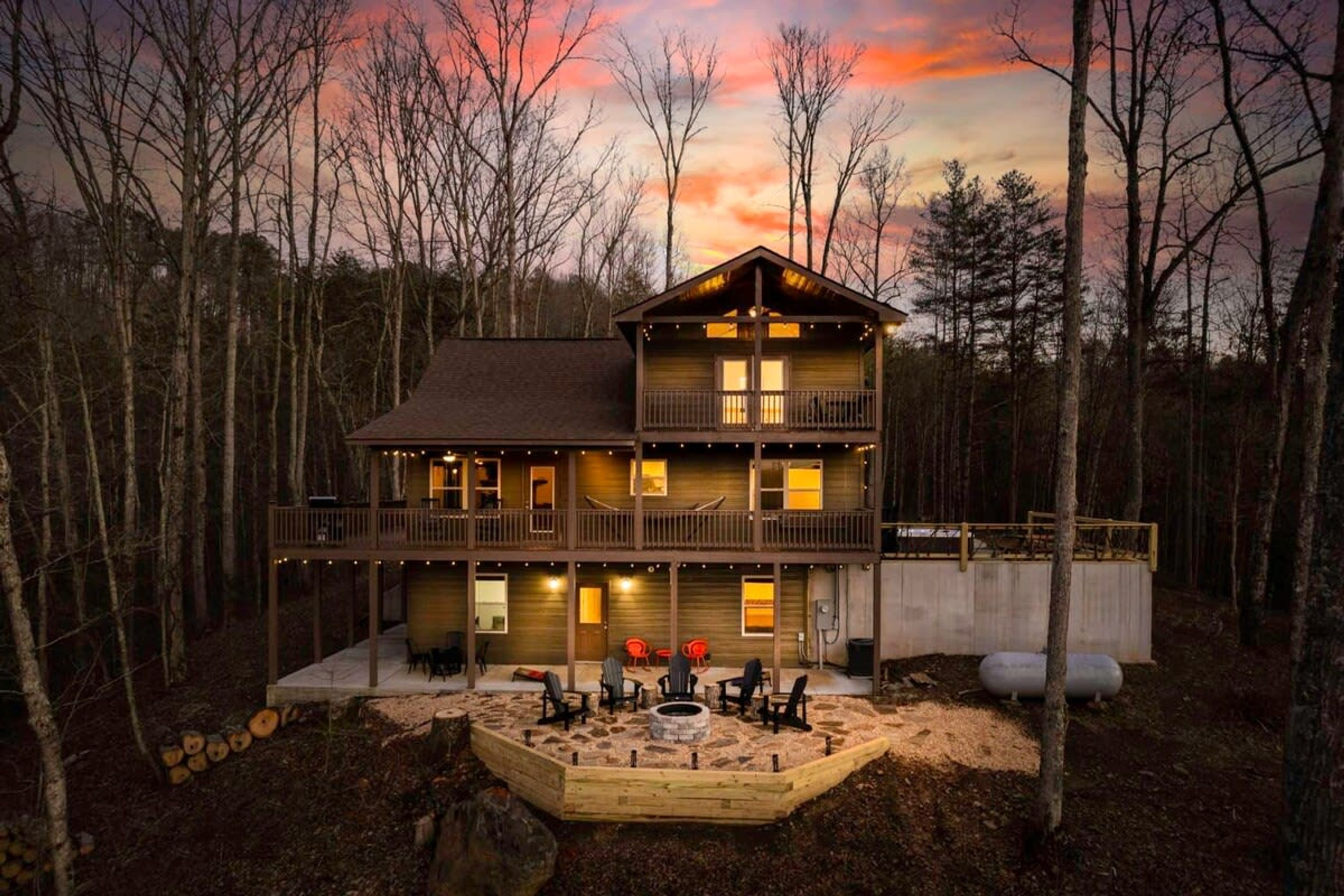A two-story log cabin with a deck and outdoor seating area.