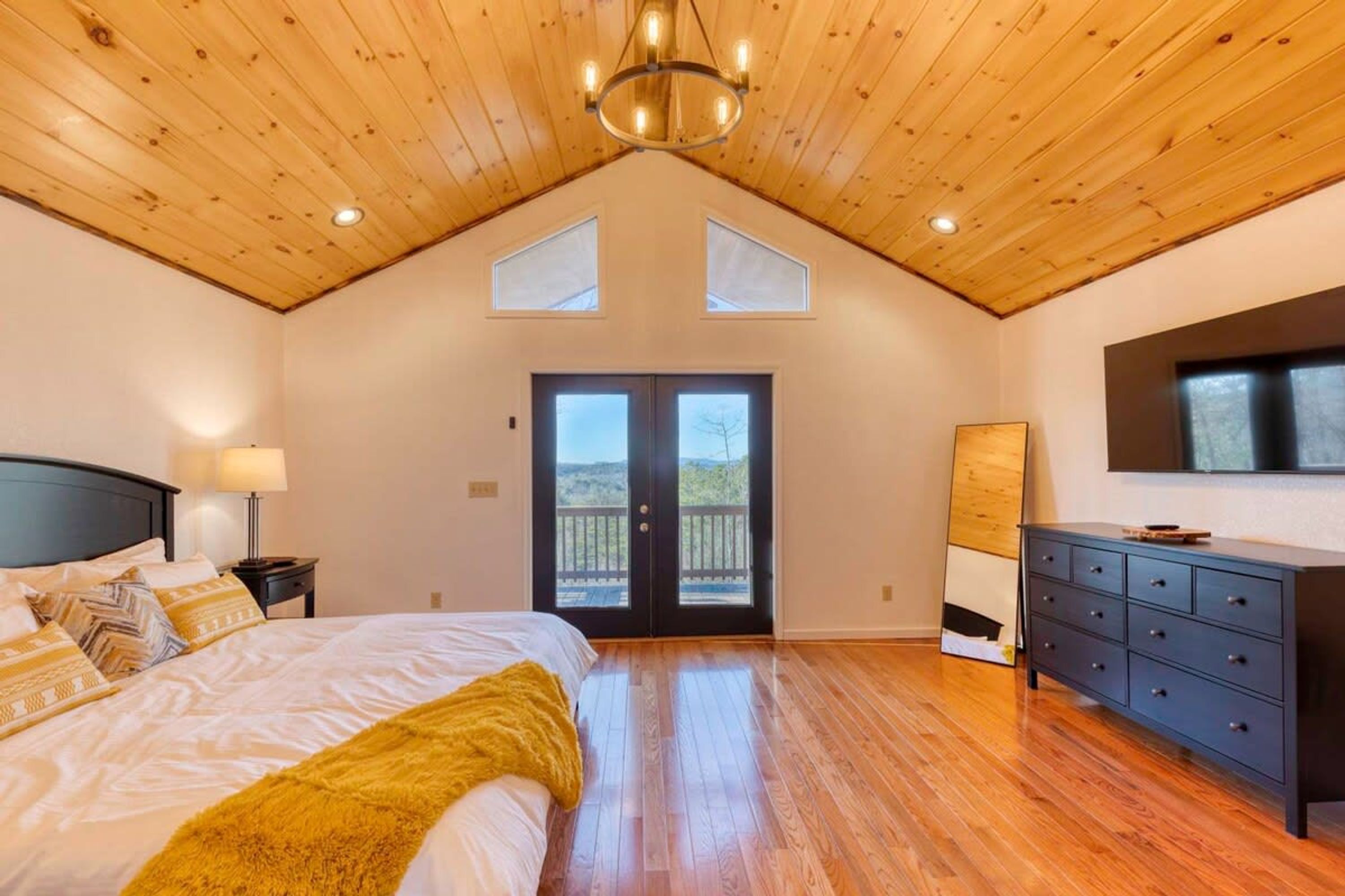 A bedroom with a bed, a dresser, a nightstand, a lamp, and a ceiling light fixture.