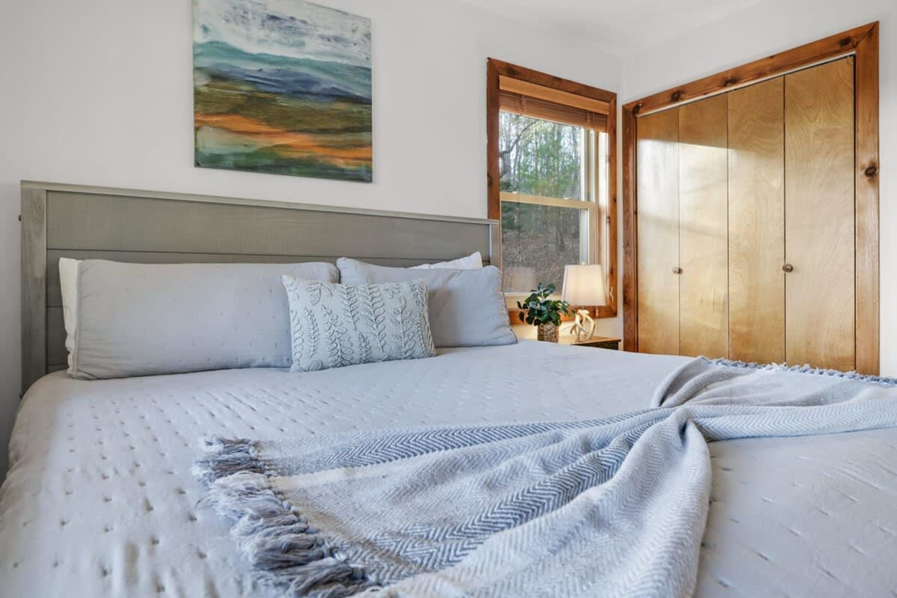 A bedroom with a bed, a nightstand, a window, and a door.