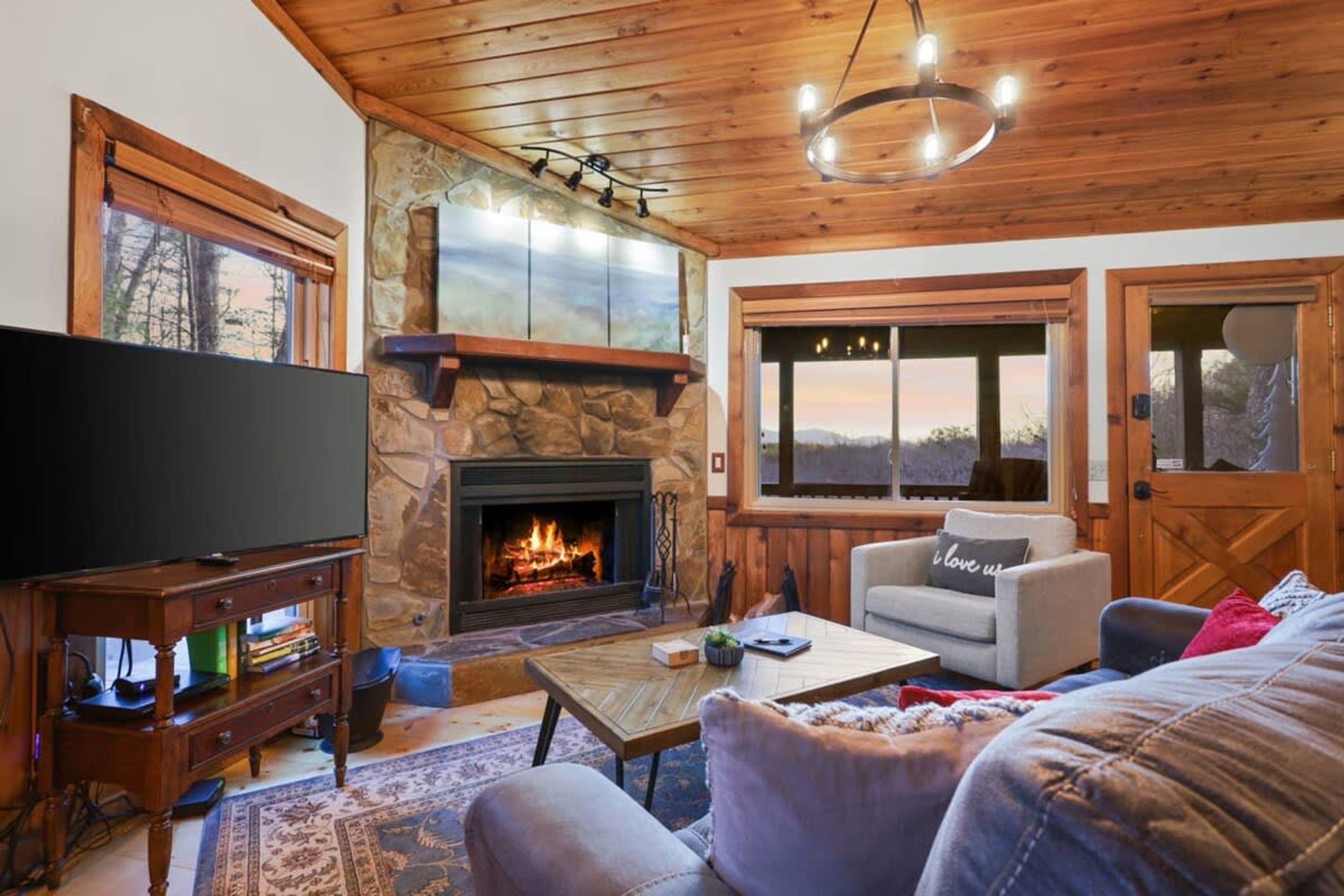 Una sala de estar acogedora con chimenea de piedra, un televisor y un espacio de estar confortable.