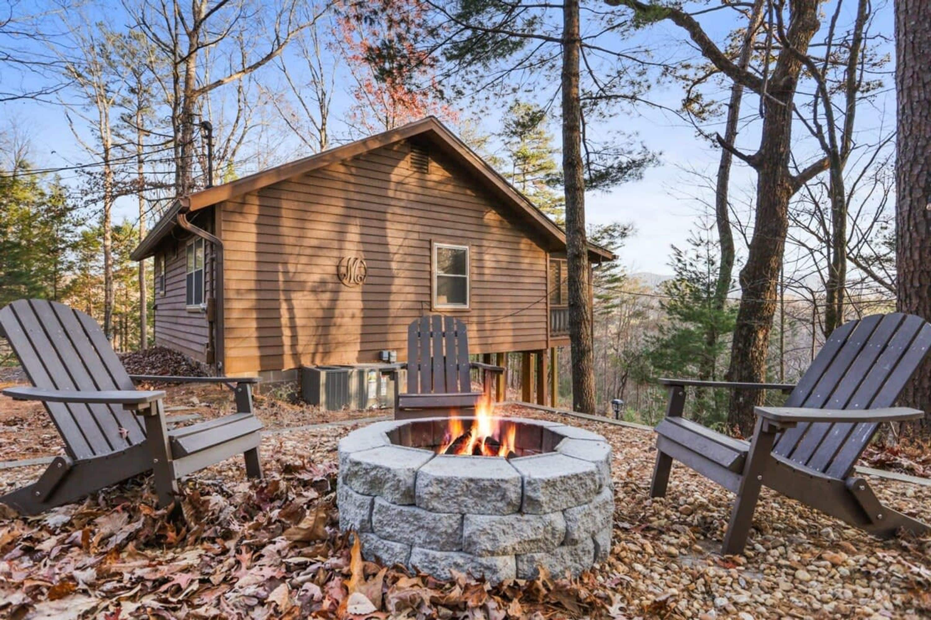 Une cabane avec un foyer en pierre, entourée de fauteuils Adirondack.