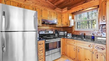 Una cocina moderna con armarios de madera, electrodomésticos de acero inoxidable y un ventanal con vista a árboles.