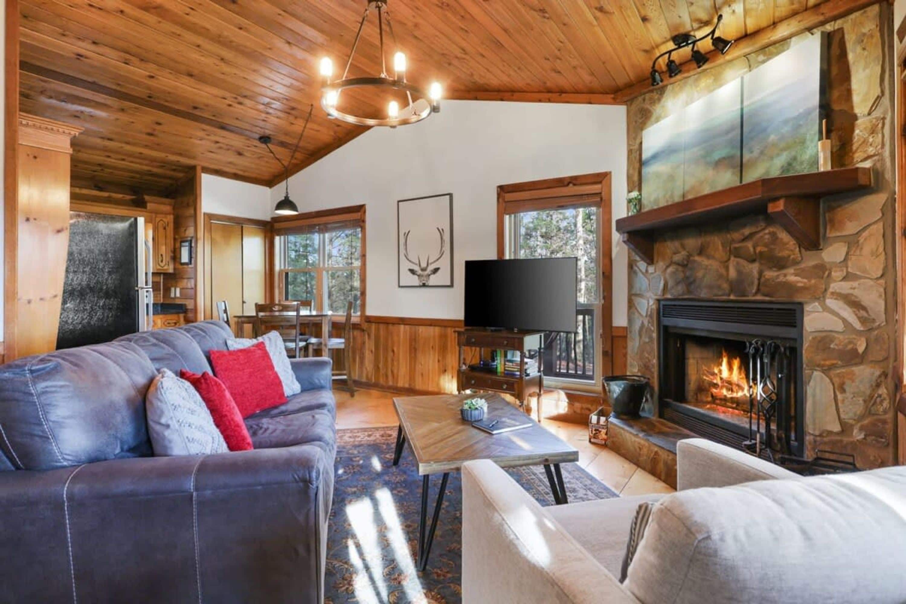 A cozy living room with a stone fireplace, a leather sofa, and a television.