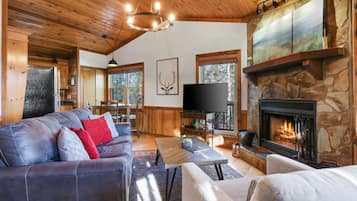 A cozy living room with a stone fireplace, a leather sofa, and a television.