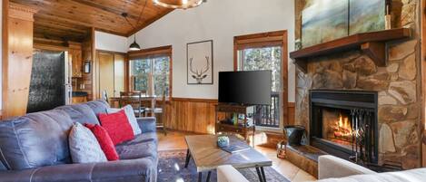 A cozy living room with a stone fireplace, a leather sofa, and a television.