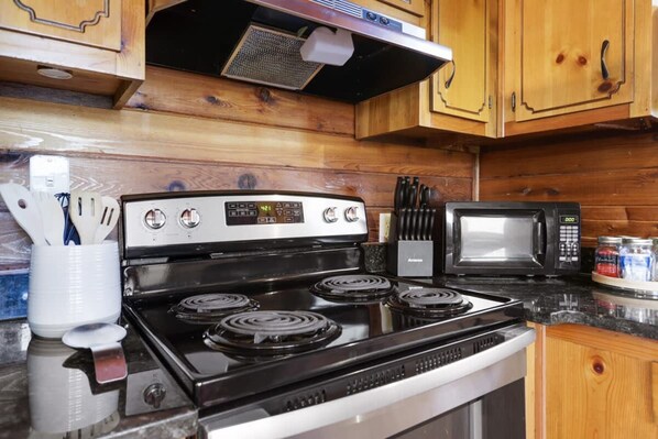 A kitchen with a stove, microwave, and wooden cabinets. - Mountain Views Hot Tub Fire Pit BBQ (Blue Ridge)
