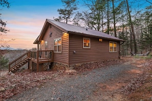 A wooden cabin with a porch and a staircase, surrounded by trees and a gravel driveway. - Mountain Views Hot Tub Fire Pit BBQ (Blue Ridge)