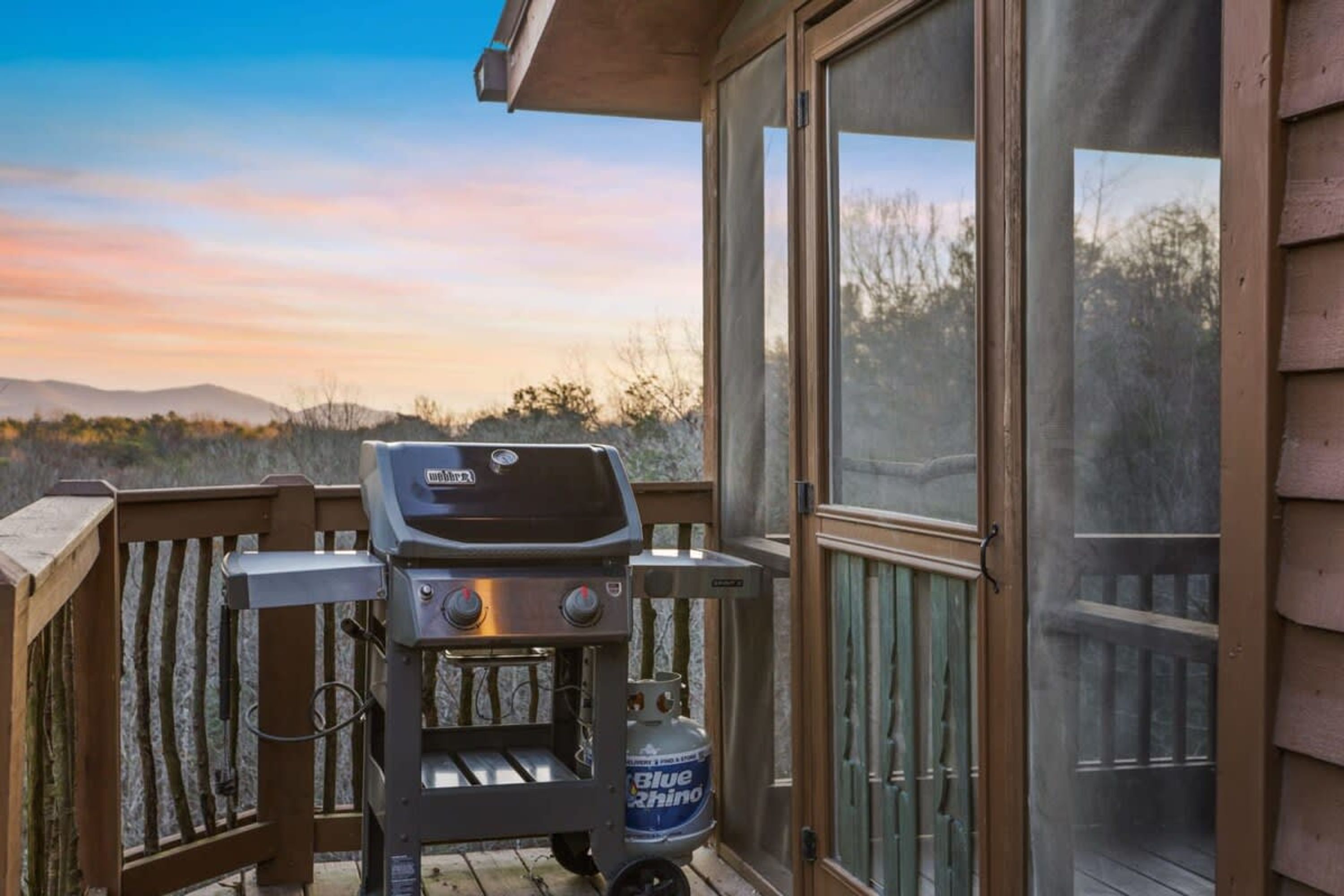 Una parrilla en una terraza de madera con vistas a un paisaje montañoso.