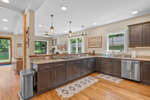 A modern kitchen with dark cabinetry, a granite countertop, and a large window. - Near Asheville Hot Tub Fire Pit BBQ (Mills River)