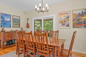 Ein Essbereich mit Holztisch und -stühlen, einer Chandelüster und Wandkunst, die den Blue Ridge Parkway zeigt.