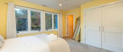 Une chambre avec un lit, un ventilateur de plafond, une grande fenêtre et une armoire.