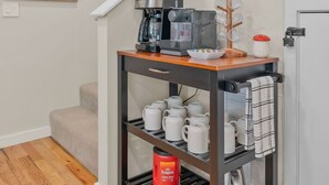 Ett kök med en kaffemaskin, en hylla med böcker och en kaffestation med muggar och en vattenkokare.