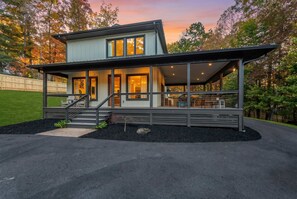 A modern two-story house with a covered porch, a staircase leading to the upper level, and a well-maintained lawn. - Near Asheville Hot Tub Fire Pit BBQ (Mills River)
