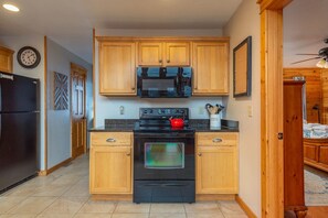 A modern kitchen with wooden cabinets, a black refrigerator, a microwave, a stove, and an oven. - 2 Deck Views Pool Table Hot Tub Spacious (Mars Hill)