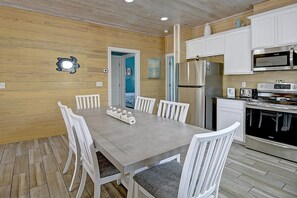 Une cuisine moderne avec des meubles blancs, des appareils électroménagers en acier inoxydable et un plancher en bois.