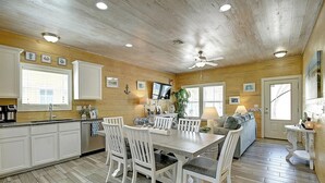 A wooden interior with a dining area, kitchen, and living space. - Toucan Tango- Golf Cart Friendly 3BD Home (Port Aransas)