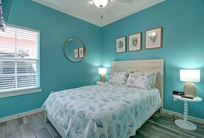 Une chambre à coucher avec un lit, un miroir rond et trois tableaux encadrés accrochés au mur.