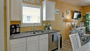 A kitchen with white cabinets, a stainless steel sink, and a window with blinds. - Toucan Tango- Golf Cart Friendly 3BD Home (Port Aransas)