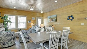 A dining area with a wooden ceiling, a ceiling fan, and a table with white chairs. - Toucan Tango- Golf Cart Friendly 3BD Home (Port Aransas)