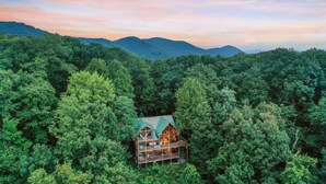 A multi-story wooden cabin surrounded by dense forest, with a view of distant mountains. - Views For Miles Hot Tub Pool Table Poker Table (Ellijay)