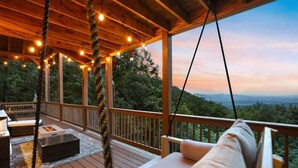 A wooden deck with a swing chair, outdoor seating, and a view of the mountains. - Views For Miles Hot Tub Pool Table Poker Table (Ellijay)