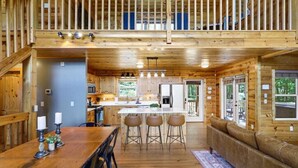 A wooden cabin interior with a dining area, kitchen, and seating space. - Views For Miles Hot Tub Pool Table Poker Table (Ellijay)