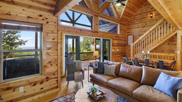 A wooden interior with a large sofa, a dining table, and a staircase. - Views For Miles Hot Tub Pool Table Poker Table (Ellijay)