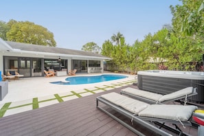 A modern outdoor pool area with lounge chairs, a hot tub, and a wooden deck. - Resort Style Backyard Heated Pool Hot Tub Fire Pit (Fort Lauderdale)