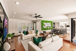 A modern living room with a sofa, coffee table, and a dining area with chairs and a table. - Resort Style Backyard Heated Pool Hot Tub Fire Pit (Fort Lauderdale)
