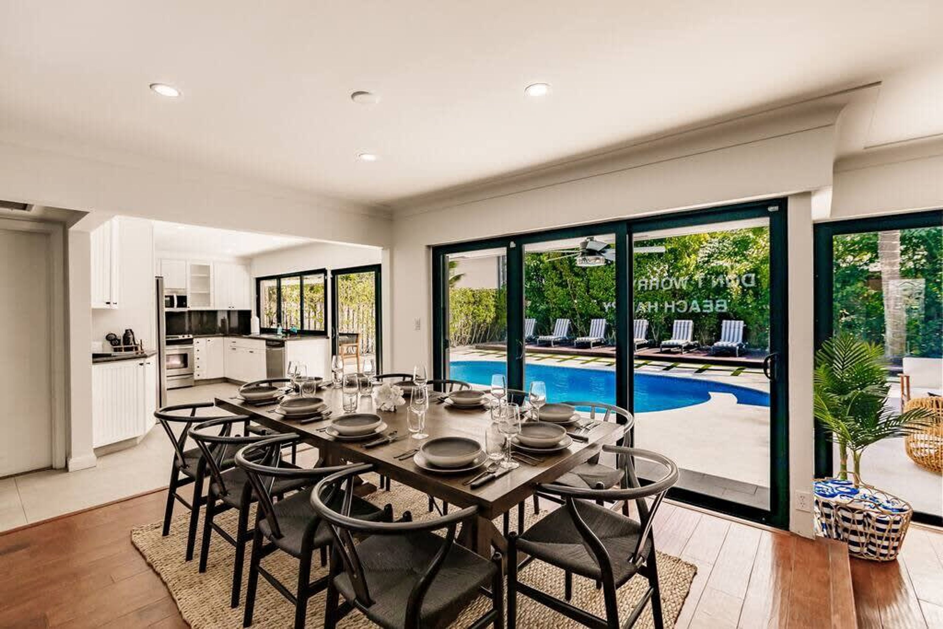 A dining area with a pool view, modern kitchen, and large sliding glass doors.