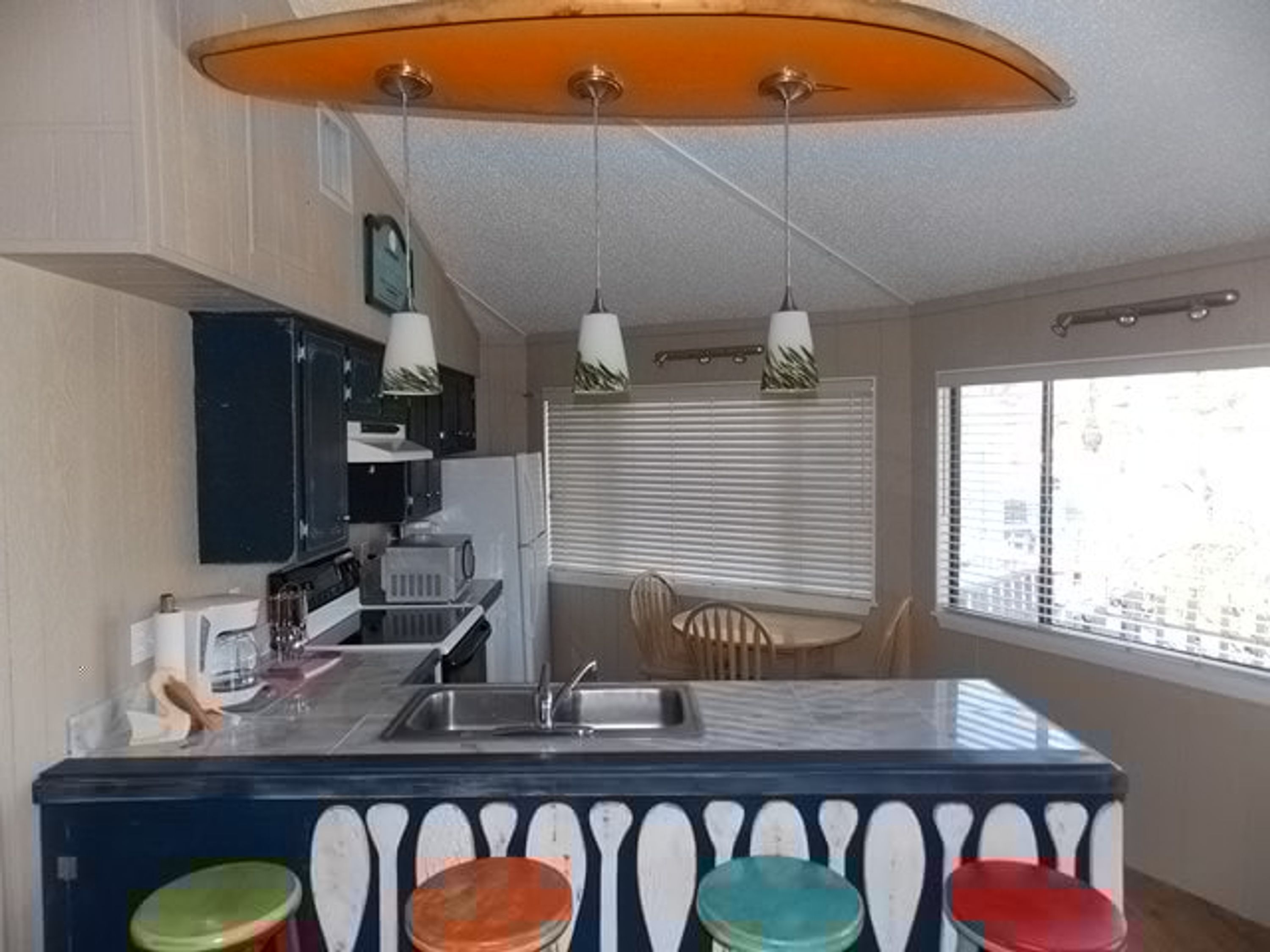 A kitchen with a bar area, a dining table, and a window with blinds.