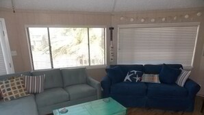 Ein Wohnzimmer mit einem grauen Sofa, einem blauen Sofa und einem grünen Couchtisch.
