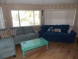 Ein Wohnzimmer mit einem grauen Sofa, einem blauen Sofa und einem grünen Couchtisch.